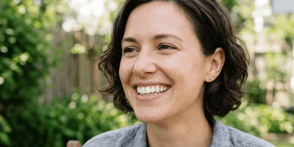 how-do-i-know-if-i-have-dry-socket-mcdougalldds - McDougall PhD, DDS | Tulsa Dentist Near Me | Tulsa, OK Close-up of a smiling woman with short dark hair outdoors in a sunny garden.